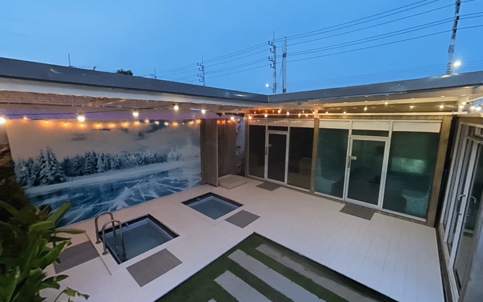 The recovery garden at dusk, with two ice baths, the snow mural and the sauna